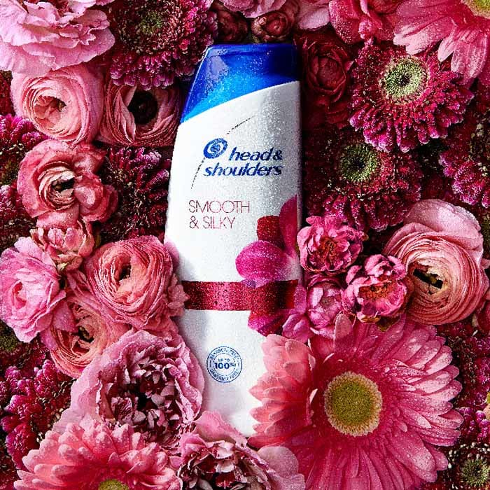 Head&Shoulders Smooth & Silky Shampoo bottle between pink flowers: roses and gerberas.