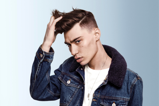 Young man with modern hairstyle touching his hair.