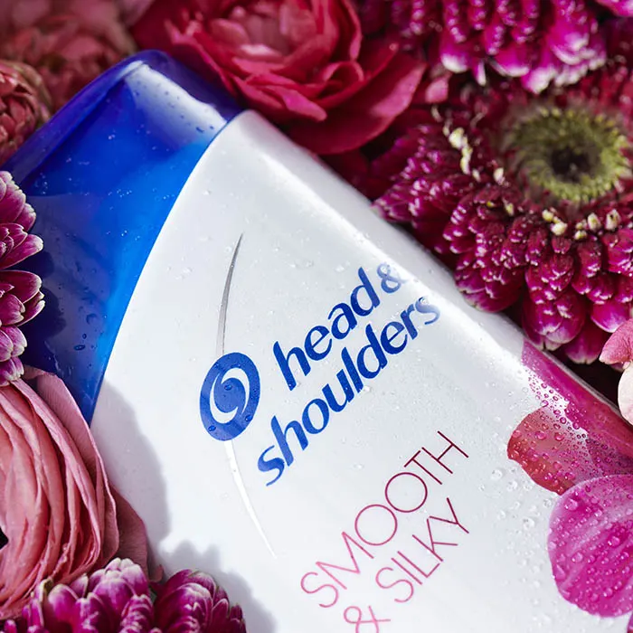 Head&Shoulders Smooth&Silky shampoo bottle lying in pink flowers, zoomed .