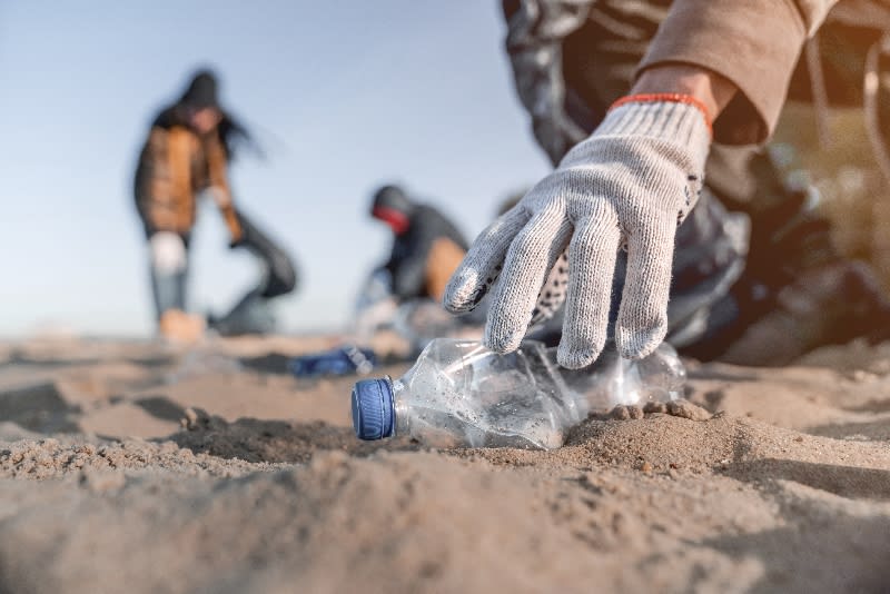 People collecting plastic bottles and other trash at the beach