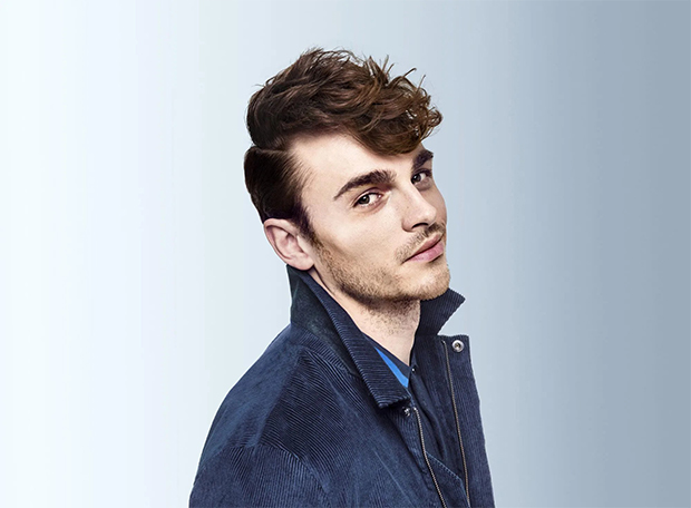 Young man looking at the screen with wavy hair on blue background