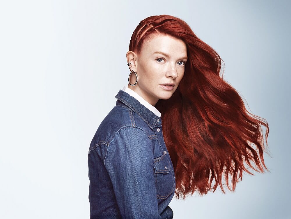 A girl with red flowing hair stands sideways, staring at the screen