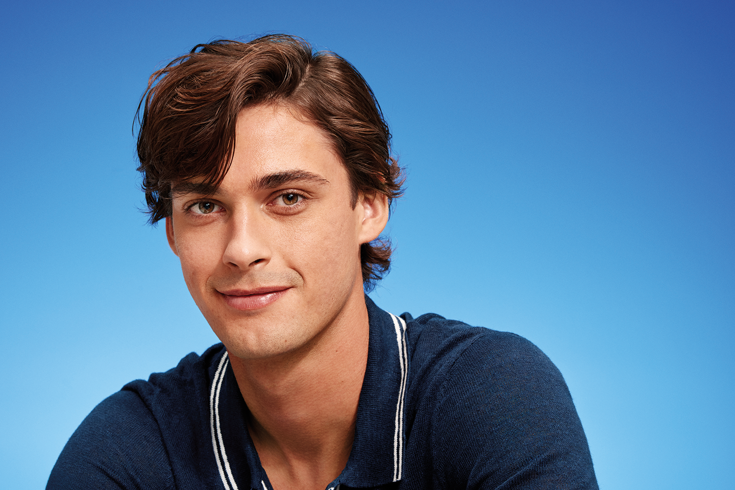 A young man with healthy hair smiles slightly at the camera.