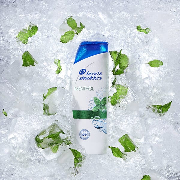 Head & Shoulders Menthol Fresh bottle partially covered with ice and mint leaves between the ice.