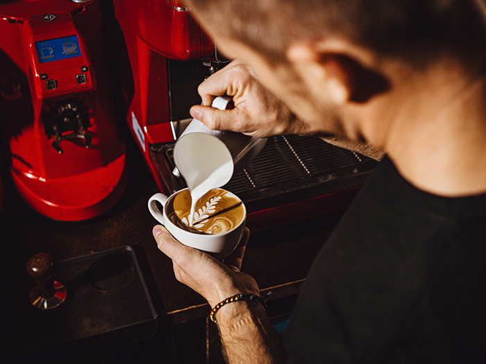 Barista making latte art to a coffee