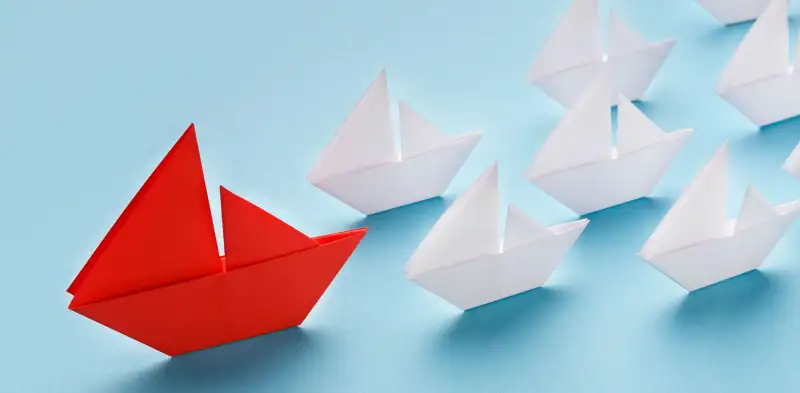 red paper boat leading white paper boats on a blue background, marketing okrs