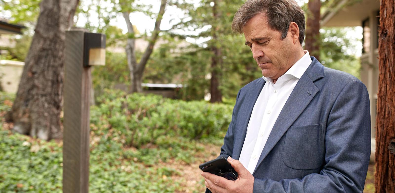 Bing Gordon outdoors looking at mobile phone