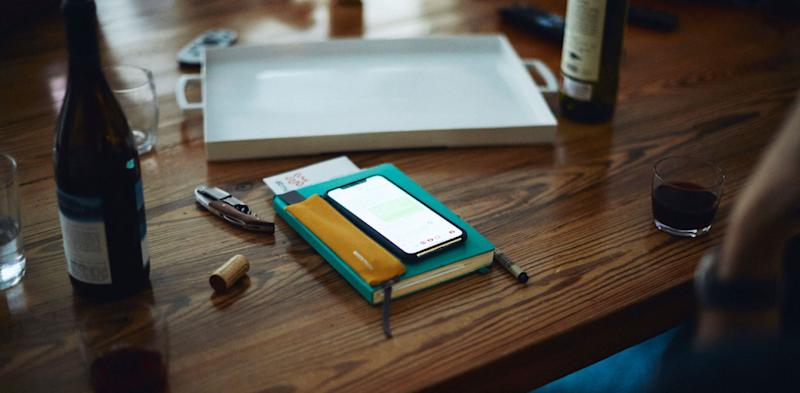 phone on book on a wooden table with a bottle of wine at apartment therapy