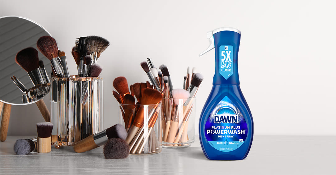 Pinceles de maquillaje en el vaso, a la derecha está el paquete Dawn Platinum Plus Powerwash