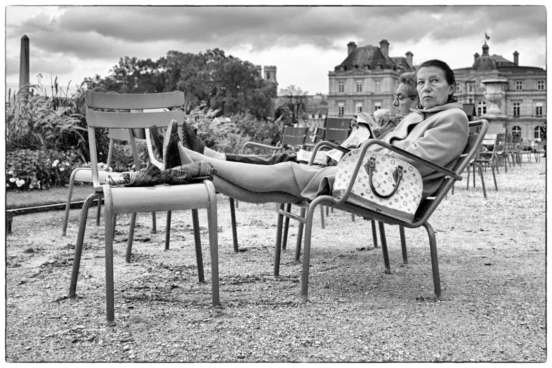 Black and White photo of woman sitting in reclining chair in the Jardins Luxembourg, Paris France