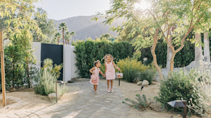 Two young girls playing with Easter baskets in a back yard.