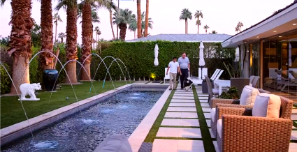A couple in their Palm Springs home backyard walking by the pool. 