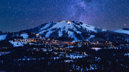 View of Park City Resort during the winter at night with all light illuminated and the Milky Way overhead.