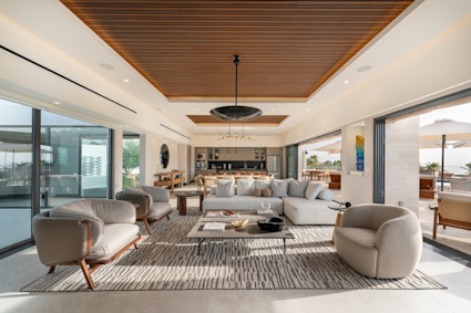 Marea living room with furniture arranged around a coffee table with floor to ceiling windows with open sliding wall that lead to outdoor area.