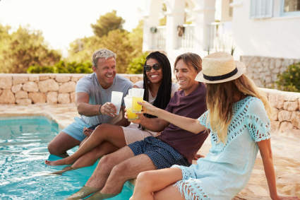 Friends have drinks at the pool of the shared second home they bought after researching timeshare alternatives.  