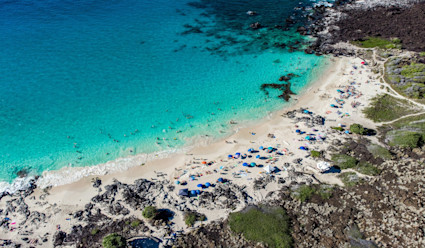Aerial view of a large bay with a white sand beach and turquoise waters.