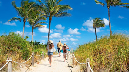 A family enjoys a leisurely walk along a sandy path leading to one of the best East Coast beaches.