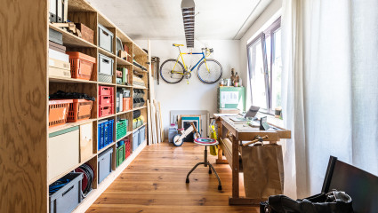 A workbench and a shelf full of bins fill the space of a hobby room, one of the most popular zen room ideas.