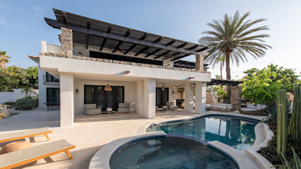 Outdoor pool area with circular hot tub and rectangular pool with poolside lounge area.