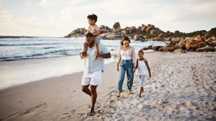 A family of four walk along the beach at one of the best family vacation spots.