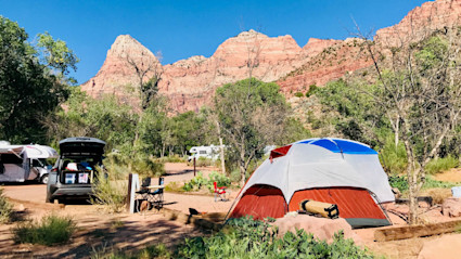 Campsite beneath towering sandstone cliffs in Zion National Park in autumn
