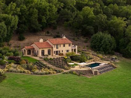 Aerial view of Mediterranean-style villa with terracotta tile roof, pool and terraced landscaping on hillside