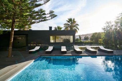black house with pool and pool chairs