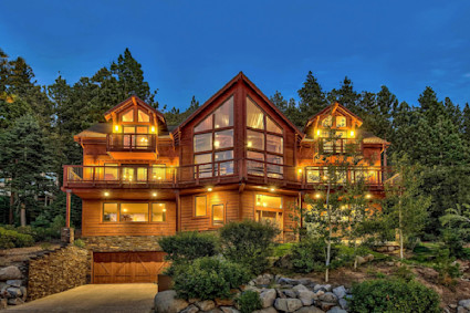 Exterior of a two-story mountain home lit up against a night sky.