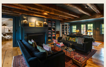 Living room featuring blue velvet couches, blue fireplace, and exposed wood beams in Infinity by Pacaso luxury home in New York.