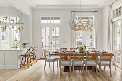 Dining room with white walls, wooden floors, large wooden table with chairs and a chandelier from Serena & Lily