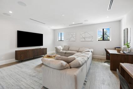 A spacious home theater room and office with a sectional sofa and desk. 