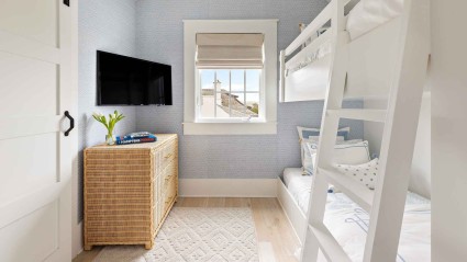 A bunk bedroom with a bunk bed, TV and storage chest