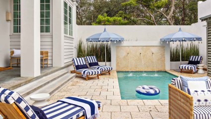 Relaxing pool area featuring blue and white striped chairs and umbrellas