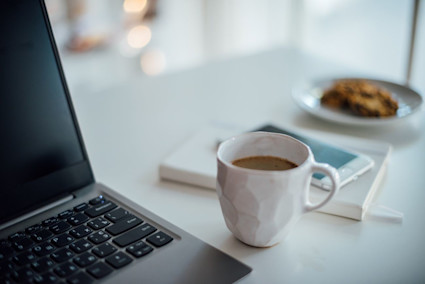 coffee cup on desk with compter and notebook