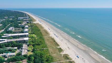 An aerial view displays the long, sparsely populated stretch of sand at Coligny Beach, one of the best beaches for kids in the South.