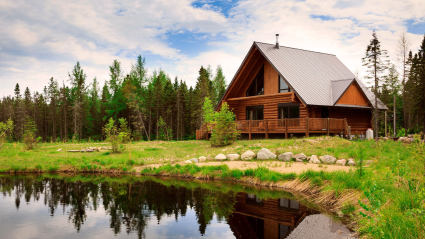 A luxury cabin that serves as a second home in a forest near a pond.