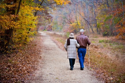 Senior couple walking down a path during autumn.