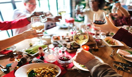 A small group of people raising their wine glasses around a holiday dinner table.