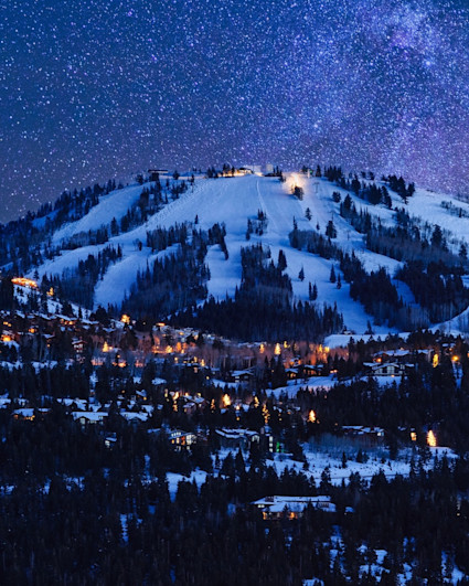 View of Park City Resort during the winter at night with all light illuminated and the Milky Way overhead.