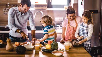 A family of four makes dinner in the kitchen of their second home, just one of the activities that make for a happier home.