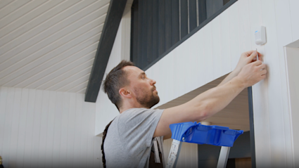 A Pacaso home managers on a ladder fixing a thermometer in a Pacaso home.