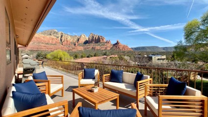 A serene patio of a Sedona vacation home with comfortable chairs overlooking majestic red rock mountains in the distance