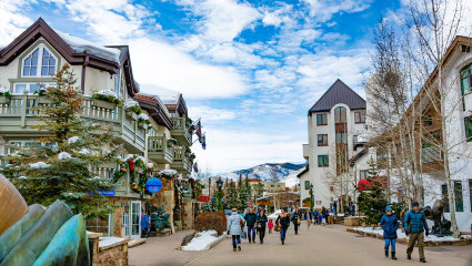People walk through the streets of Vail, Colorado with mountains in the background, embodying why it’s one of the best places for a second home.