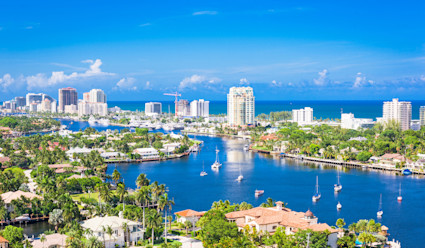 Aerial view of buildings and homes surrounding a body of water with the ocean in the background.