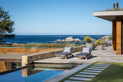 Outdoor patio with a pool in front of the ocean