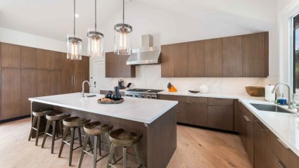 An immaculate second home kitchen in Napa featuring sleek cabinetry, granite countertops, and a large island with bar stools for casual dining