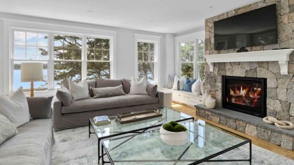 A cozy living room with a stone fireplace, comfortable couches and water views