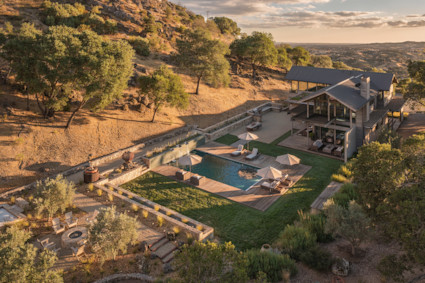 Aerial view of a hillside retreat at golden hour with a terraced pool, lawns, and fire pit overlooking oak-dotted valleys.Aerial view of a hillside retreat at golden hour with a terraced pool, lawns, and fire pit overlooking oak-dotted valleys.