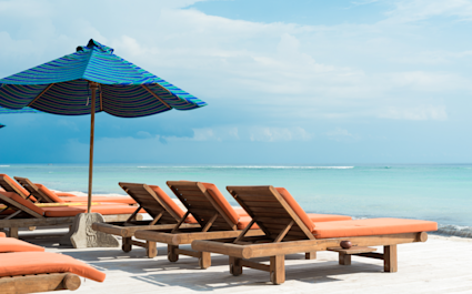 orange chairs on a beach with blue umbrella