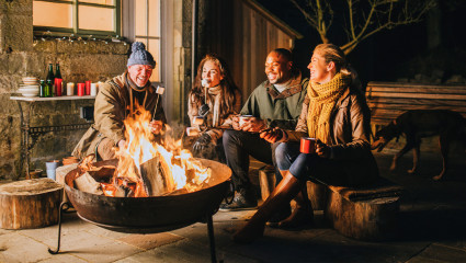 A group of friends laugh in conversation as they cook marshmallows at their newly installed fire pit, making a happier home.